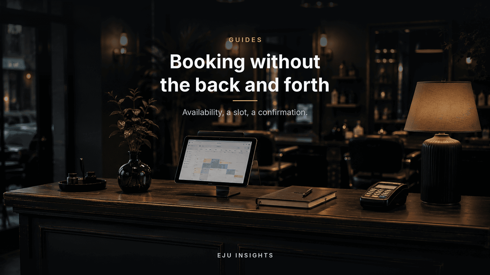 A dimly lit salon reception counter at dusk with a tablet showing a booking calendar, a diary, and a card machine.